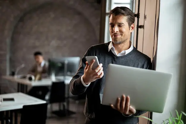 Profissional de empresa usando notebook e celular